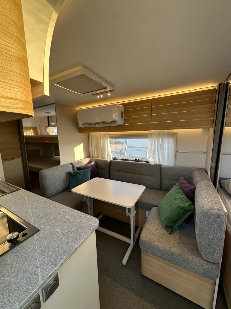 אזור הסלון בקרוואן Adria 573PT – פינת ישיבה נפתחת, תאורה נעימה וחלונות נוף
